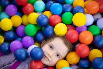 Fototapeta na wymiar Little cute toddler girl play with plastic balls in children playcenter. Toddler girl in Day Care Play Room