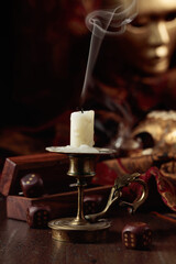 Extinguished candle, dice, and carnival masks on an old wooden table.
