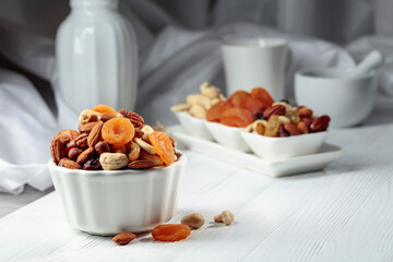 Dried fruits and assorted nuts on a white table.
