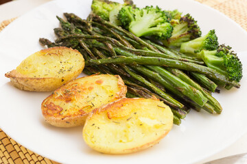 lean dish of cooked fried inflorescences of broccoli, asparagus growth and baked potatoes and Provencal herbs