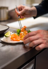 chef cooking slice salmon fish and shrimp with salad on kitchen