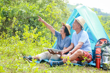 Asian elderly couple happy to travel in nature Set up a tent and camp in the forest. Tourism concept of the elderly in retirement age. Tourists and travelers trekking
