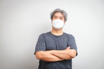 Portrait of a fat Asian man wearing a mask to prevent the virus. man with white hair Wear a mask, stand with your arms crossed. health care concept
