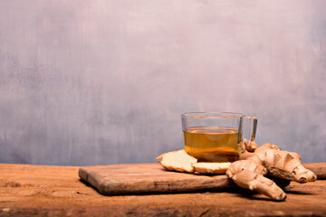 Hot ginger-infused cup on a white table with sliced ginger root in a bowl. Top view.