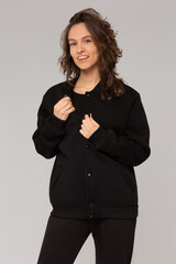 Smiling woman with thick curly hair in a black suit of hoodies and sweatpants. Mock-up.