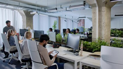 Successful young professional people working in modern IT company using computers and headphones typing on keyboard. Efficient workers of call center supporting customers talking helping. - Powered by Adobe