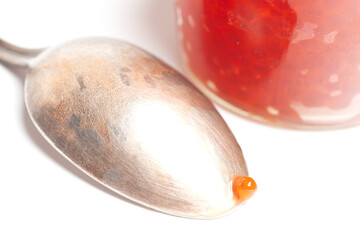 Glass jar and spoon with delicious red caviar isolated on white background.