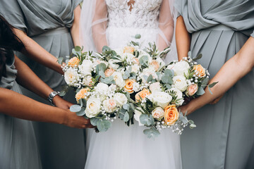 Wedding. A bride in a white dress and bridesmaids in identical dresses hold bouquets of flowers and greenery in their hands