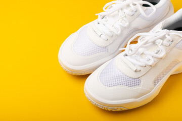 A pair of white shoes on a yellow background. White stylish sneakers. STREET STYLE.Sports concept, unisex, sports shoes, lifestyle, concept, product photo, levitation concept, streetwear.