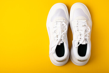 A pair of white shoes on a yellow background. White stylish sneakers. STREET STYLE.Sports concept, unisex, sports shoes, lifestyle, concept, product photo, levitation concept, streetwear.