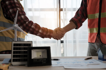 Shaking hands, Professional engineering solar planning blueprint with team, Wind turbine and Solar...