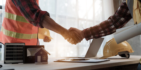 Shaking hands, Professional engineering solar planning blueprint with team, Wind turbine and Solar Energy Electrical Engineer concept.