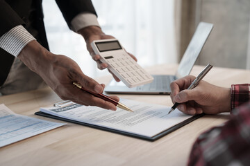 Holding calculator, showing house cost and interest, Credit approver, businessman in male suit and house toy model mockup Home loan mortgage approval concept. After signing the contract