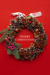 Christmas wreath with bright shiny decorations on red background