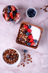 Yogurt with chocolate granola, strawberry and blueberry served in a bowl and a glass. Healthy breakfast. Top view