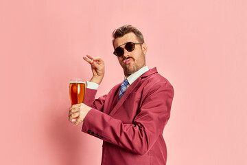 Portrait of stylish emotive man in a suit and snglasses posing with glass of lager beer isolated on...