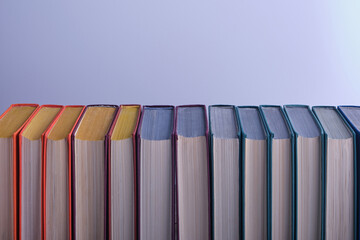 Fototapeta premium Turned by the cut edge of the book in a long row, you can see multi-colored fabric covers, textured paper. Education, book publishing, love of reading