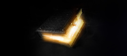 Mysterious glowing antique book on a dark background. Horizontal banner with copy space for popular...