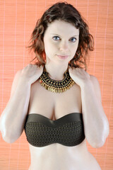 Portrait of a beautiful brunette woman wearing bandeau bikini top and necklace in studio
