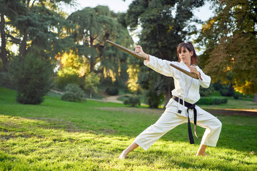 Martial arts teacher in white kimono is practicing with tonfa. High quality photo