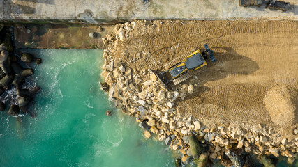 Aerial view of waterfront construction site with excavator. Bulldozer working on a breakwater construction - Powered by Adobe