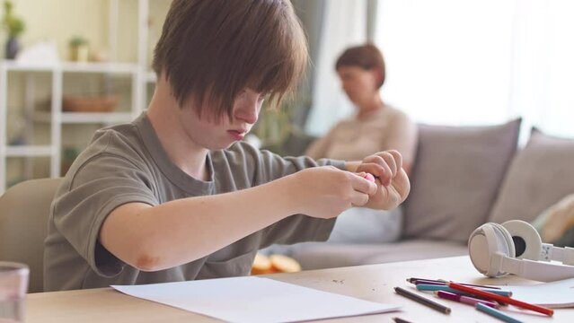 14 year old girl with down syndrome sharpening her pencils while studying at home