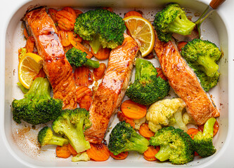 Top view close up of healthy baked fish salmon steaks, broccoli, cauliflower, carrot in casserole dish. Cooking a delicious low carb dinner, healthy nutrition concept.