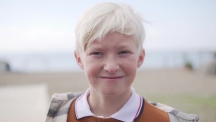 Close-up, a blond boy with freckles on his face against the backdrop of the sea and sky in autumn in Turkey, Alanya.