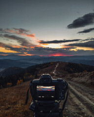 Camera on tripod making recording of mountains sunset