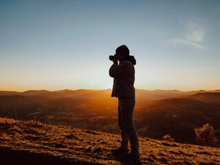 A man photographer taking pictures in front of autumn mountains landscape