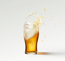Splashes and drops. Glass of frothy light lager beer isolated over grey background. Concept of...