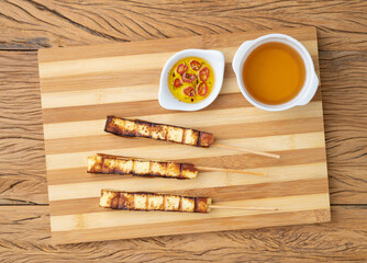 Grilled Rennet or Coalho cheese on a wooden board with sugar syrup and pepper