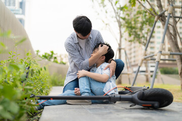 Young Asia boy fell from electric scooter bike sitting on the floor and feeling pain and get injury...