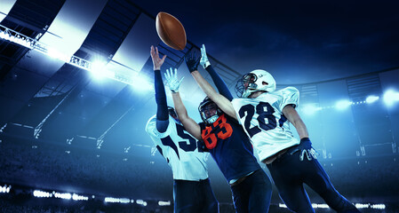 In a jump. Three active american football players in motions, playing, catching ball isolated at...