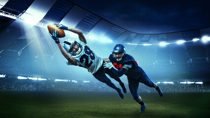Opponents. Two active american football players in motions, playing, catching ball isolated at the stadium with flashlights. Concept of sport, competition