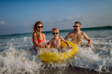 Happy family with little son enjoying time in sea in exotic country.