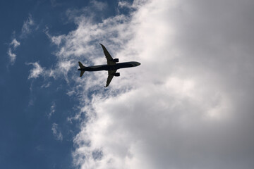 Fototapeta na wymiar Airplane flying over blue sky and clouds