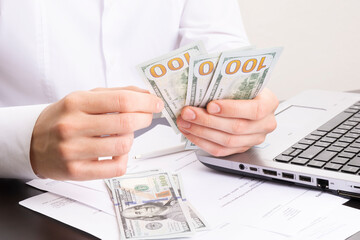 caucasian hands counting dollar banknotes on white wooden surface