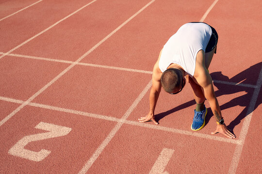 young muscular athlete is at the start of the treadmill.