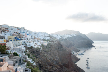 The view of Oia village at sunrise with white buildings and sea with boats