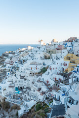 Fototapeta na wymiar The view of Oia village at sunrise with white buildings and windmills in the background