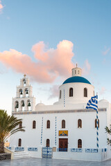 Greek orthodox church on an empty square at sunrise, greek flag on a pole