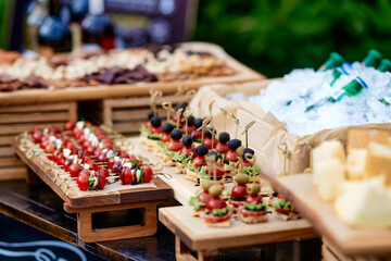Catering. Buffet on the street. Canape of tomatoes, cheese, meat, olives, lettuce. Eco wooden...
