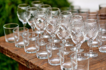 Arrangement of wine and whiskey glasses. Eco buffet in nature. Wooden table.