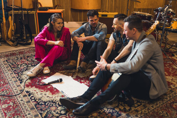 modern band members on the floor talking, the microphone is in front of them on the floor, recording studio. High quality photo