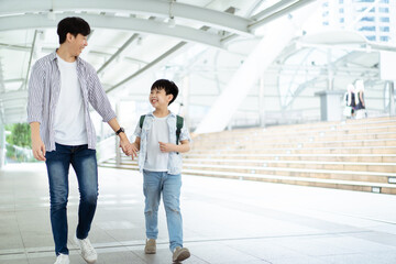 Obraz premium Father taking his son going to school, a man holding child hand while walking to school together.