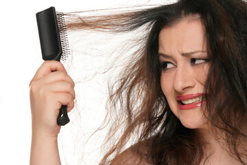 portrait of a young nervous chubby woman brusshing her messy long hair on a white background.