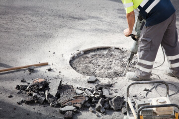 jackhammer in hands of asphalt worker logging underground and portable electric generator