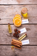 Bottles  with organic essential aroma oil  with cinnamon, anise and orange  on aged wooden background. Natural skin care products. Beauty blogging, salon treatment concept. Selective focus. 