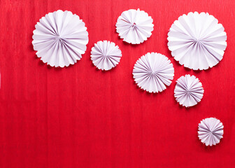  Handmade nordic decoration. White paper rosettes on  red textured  paper background.Natural, ogranic materials. Place for text. Top view. - 553244653